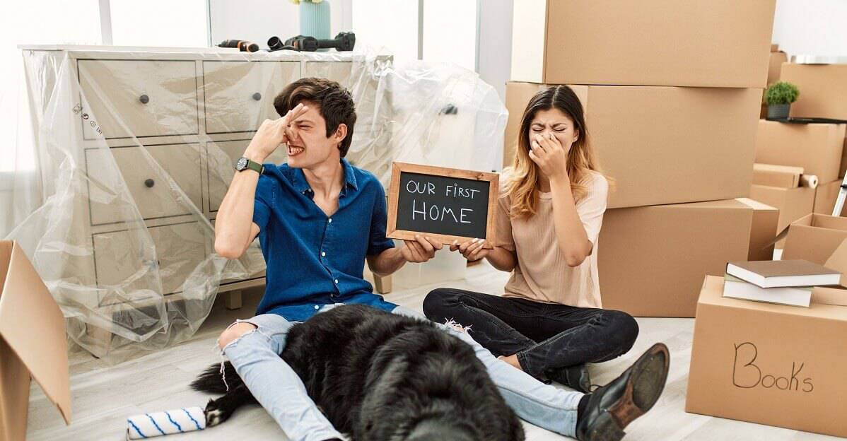 caucasian couple with dog holding our first home blackboard at new house smelling something stinky and disgusting