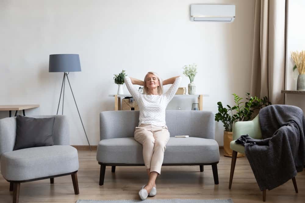 older woman sitting leaning back on couch in air conditioner room
